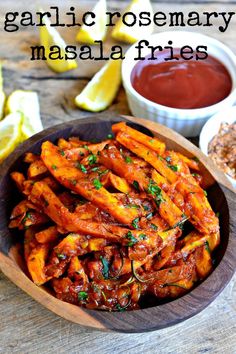 garlic rosemary masala fries in a wooden bowl with dipping sauce and lemon wedges