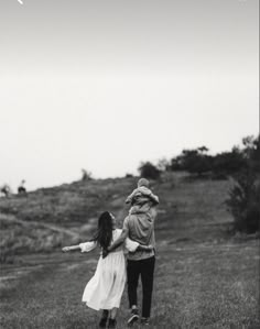 two people are walking in the grass with their arms around each other and one person is holding