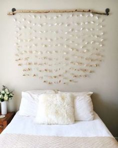 a white bed topped with pillows next to a wall mounted art piece on the wall