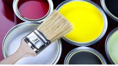 a paint can with a brush in it next to several different colors of paint cans