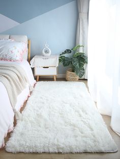 a bedroom with blue walls and white fur rugs on the floor next to a bed