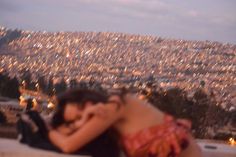 a woman laying on top of a wall next to a city