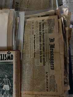 several newspapers are stacked on top of each other in front of a wall with newspaper clippings