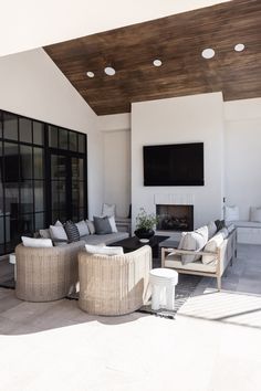 an outdoor living room with couches and television on the wall in front of it