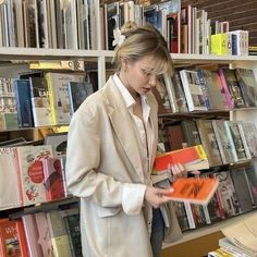 a woman standing in front of a book shelf filled with books