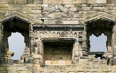 an old stone building with three windows and two horses standing in the window sill