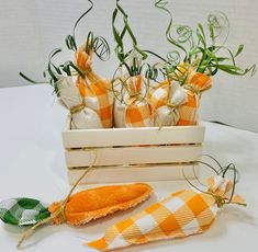 an orange and white checkered cloth is next to some carrots in a wooden box