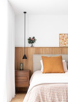 a bed sitting in a bedroom next to a wooden headboard and window with white drapes