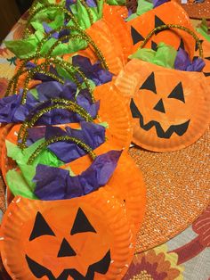 paper plates with pumpkins on them are sitting on a table covered in purple and orange tissue