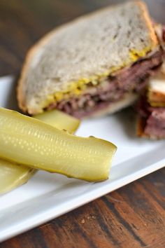 a sandwich with pickles on a white plate