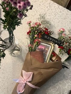 a bouquet of flowers sitting on top of a table next to a brown paper bag