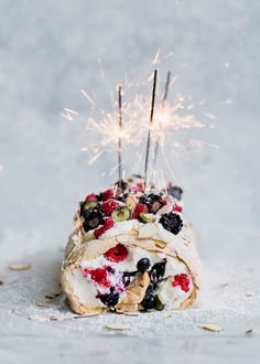 a pastry with berries, blueberries and other toppings is being lit by a sparkler