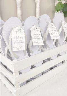 several pairs of flip flops are on display in a white crate with tags attached to them