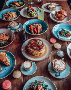 a wooden table topped with lots of plates of food