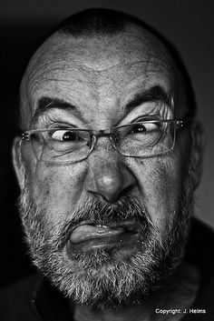 a black and white photo of a man with glasses looking at the camera while making a funny face