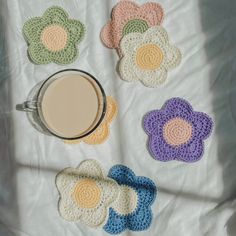 there are crocheted coasters and a cup of coffee on the bed next to each other