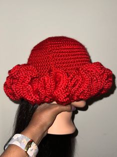 a woman wearing a red crocheted hat with ruffles on the brim