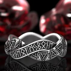 two rings that are sitting next to each other on top of a glass table with red hearts