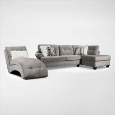 a gray couch and chair sitting next to each other on a white floor with pillows