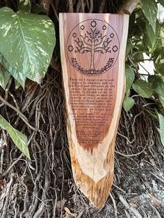 a wooden plaque sitting on top of a pile of dirt next to a tree trunk