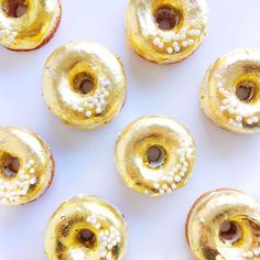 gold donuts with white sprinkles are arranged on a white tablecloth