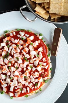 a white plate topped with food next to a bowl of crackers