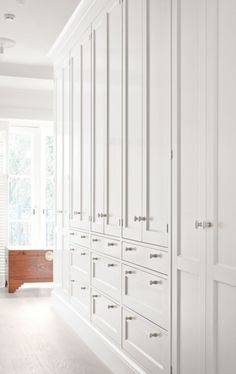 a large white closet with many drawers and doors on the wall next to a window