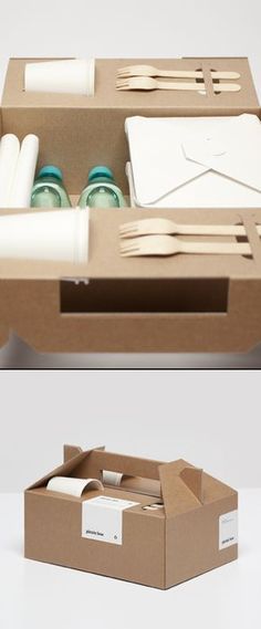 an open cardboard box with utensils and napkins in it on the table