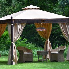 a gazebo sitting on top of a lush green field next to a table and chairs