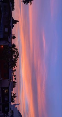 the sky is filled with pink clouds as the sun sets in the distance behind some buildings