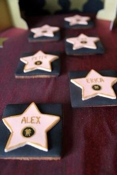 five star shaped cookies sitting on top of a red table cloth covered table with black and gold stars