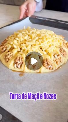 a pizza sitting on top of a pan covered in cheese and nuts, being cut into smaller pieces