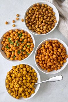 four white bowls filled with chickpeas on top of a table