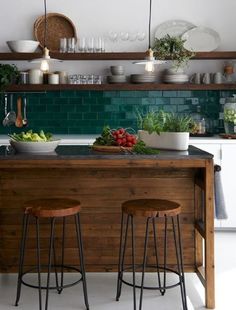 two stools sit at the center of a kitchen island with bowls of vegetables on it