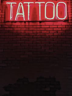 a red neon sign that says tattoo on a brick wall