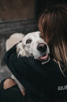 a woman holding a white dog in her arms