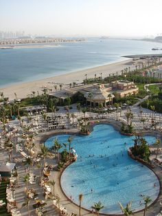 an aerial view of a beach resort and swimming pool with palm trees in the foreground