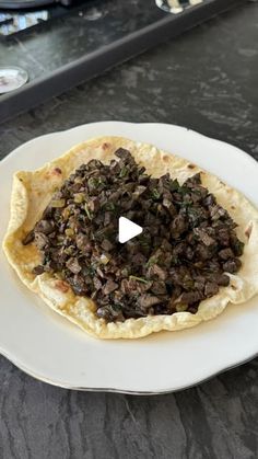 a flatbread topped with black olives on top of a white plate