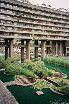 an apartment building with many balconies and plants growing in the water next to it