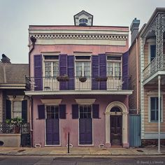 an old pink building with purple shutters and balconies