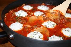 a pot filled with pasta and meatballs on top of a wooden table