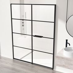 a bathroom with a glass shower door next to a white sink and black faucet