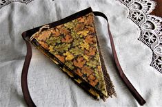 a triangle shaped piece of fabric on top of a lace doily with a brown ribbon