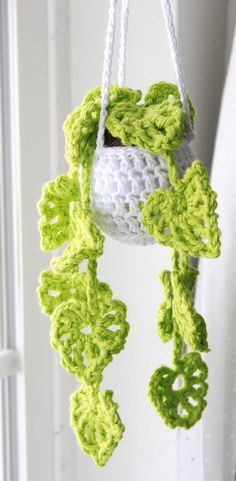 a crocheted green and white plant hanging from a hook on a door handle