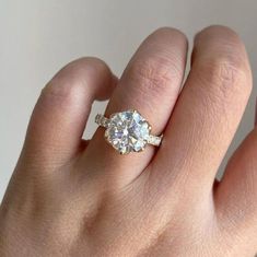 a woman's hand with a diamond ring on top of her finger, and the other hand holding an engagement ring