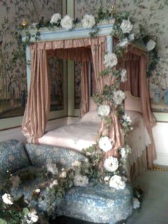 a canopy bed with flowers on it in a room filled with mirrors and couches