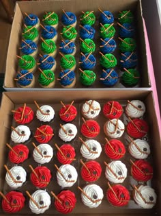 two boxes filled with different colored cupcakes on top of a table next to each other