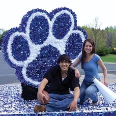 two people pose in front of a float made to look like a dog's paw