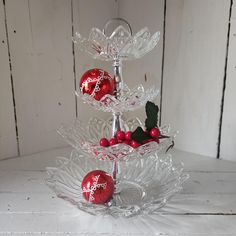 three tiered glass christmas tree with ornaments on top and red baubles in the bottom