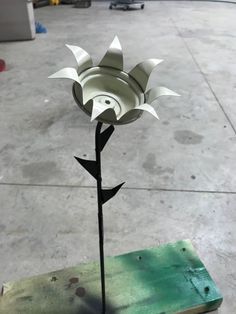 a paper flower sitting on top of a piece of wood